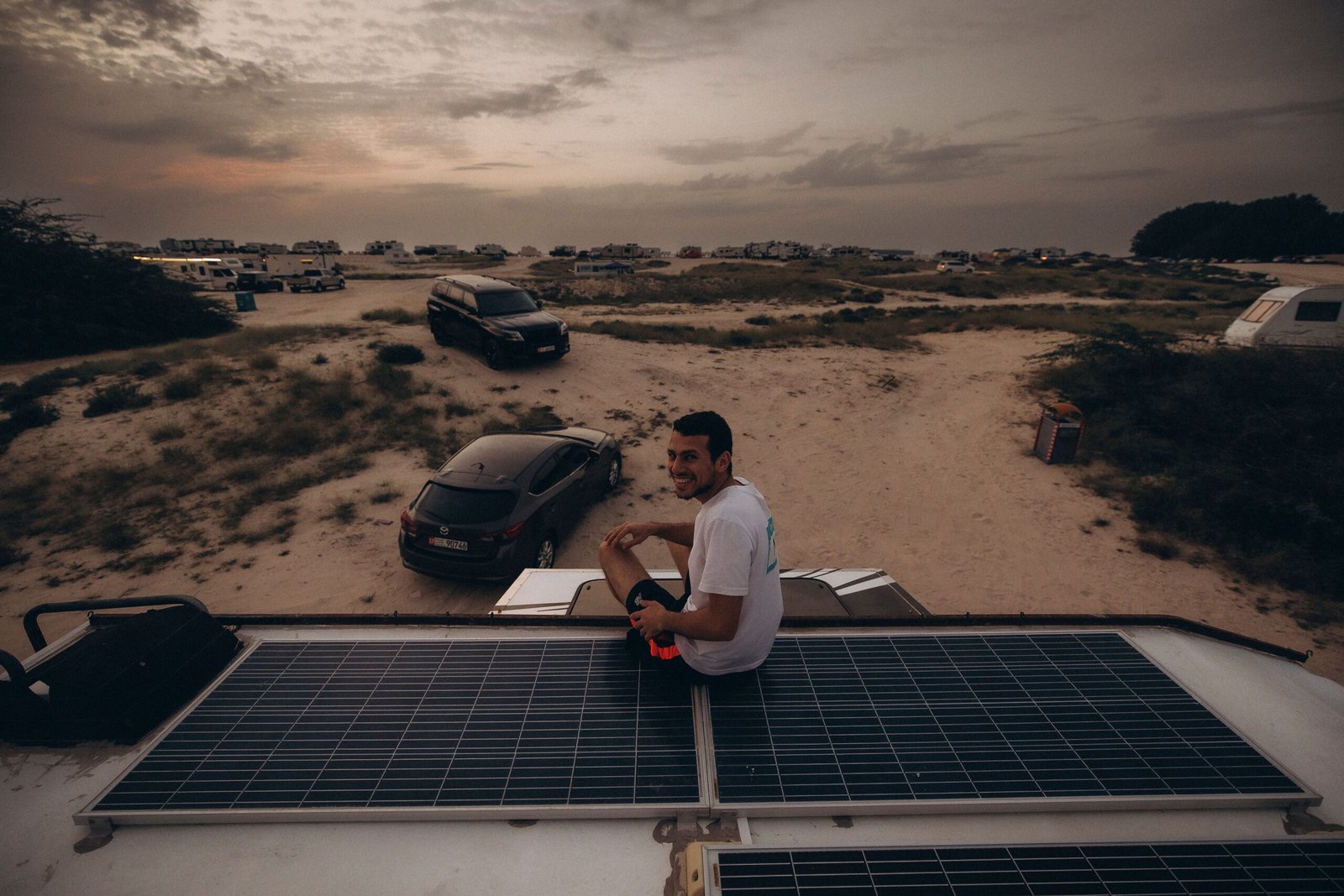 Person relaxing at sunset campsite with a solar panel and portable power station