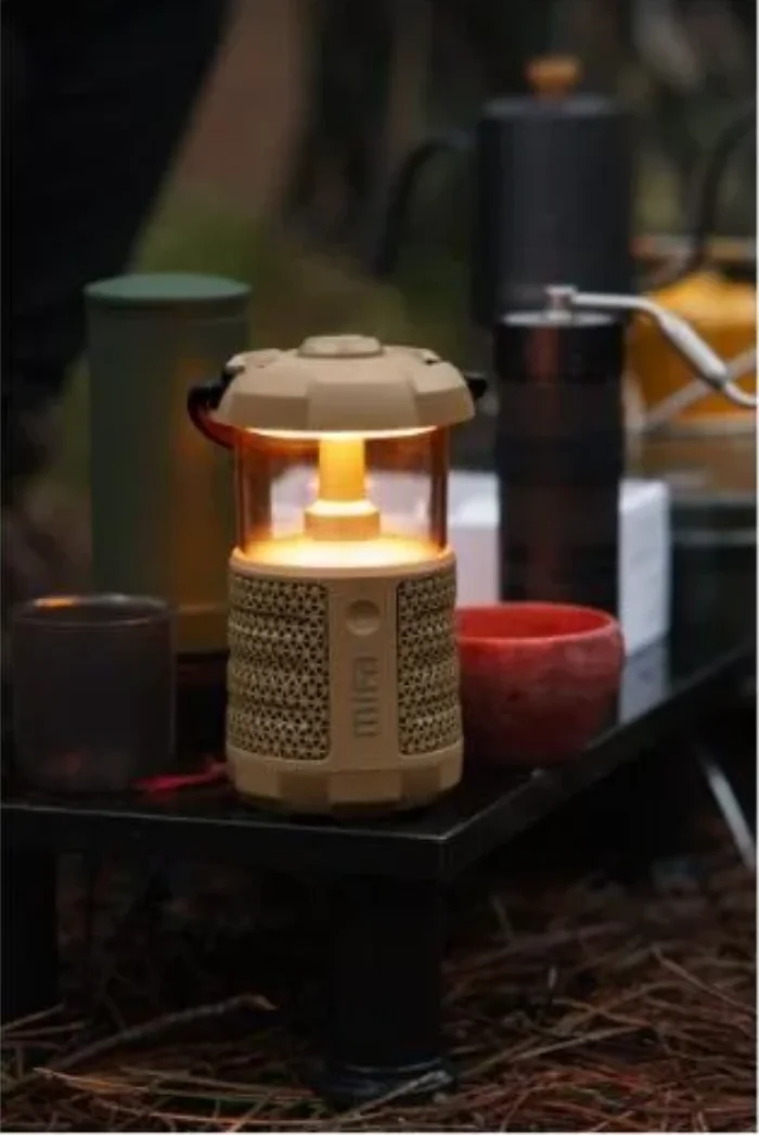 Warm lantern glowing among camping gear at dusk