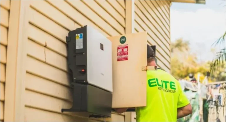 Technician installing a solar power inverter on a home exterior wall