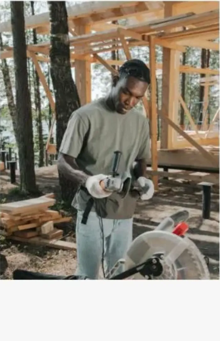 Construction worker using a corded power tool at an outdoor job site framing project